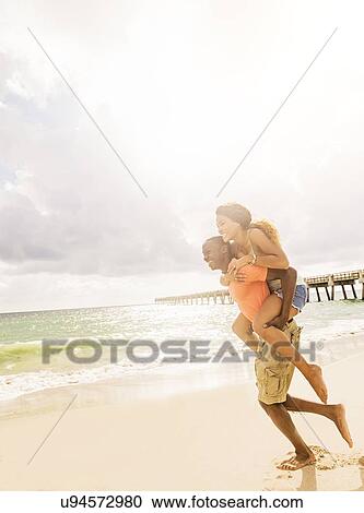 Young couple playing on beach View Large Photo Image Stock Image - Young couple playing on beach. Fotosearch