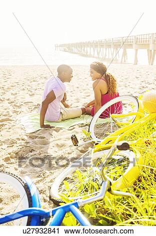 Stock Image - Young couple relaxing on beach. Fotosearch