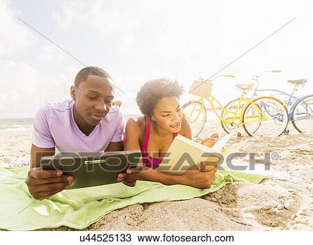 Stock Image - Young couple relaxing on beach. Fotosearch