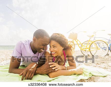 Stock Photo - Young couple relaxing on beach. Fotosearch