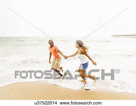 Young couple running on beach View Large Photo Image Picture - Young couple running on beach. Fotosearch