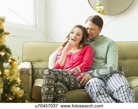 Young couple sitting on sofa at Christmas View Large Photo Image Stock Photo - Young couple sitting on sofa at Christmas. Fotosearch