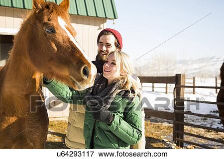 Young couple stroking horse View Large Photo Image Stock Photo - Young couple stroking horse. Fotosearch