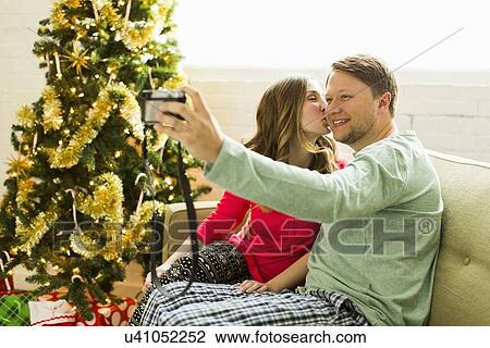 Young couple taking selfie on sofa at Christmas View Large Photo Image Stock Image - Young couple taking selfie on sofa at Christmas. Fotosearch