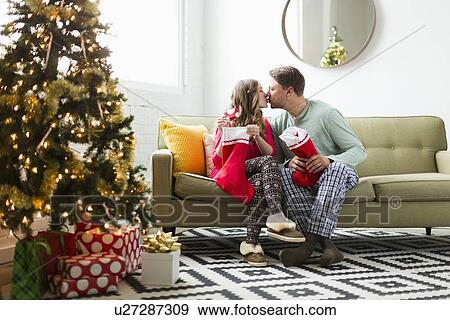 Young couple with Christmas stockings kissing on sofa View Large Photo Image Stock Photo - Young couple with Christmas stockings kissing on sofa. Fotosearch