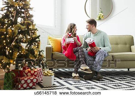 Stock Photo - Young couple with Christmas stockings on sofa. Fotosearch