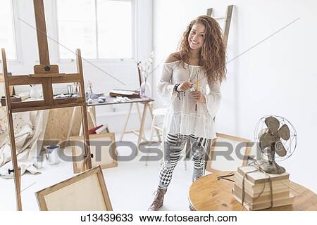 Stock Image - Young female artist in studio. Fotosearch