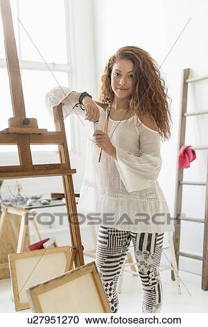 Stock Image - Young female artist in studio. Fotosearch