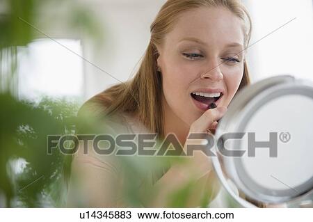 Young woman applying lipstick View Large Photo Image Stock Image - Young woman applying lipstick. Fotosearch