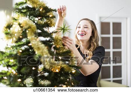 Picture - Young woman decorating Christmas tree. Fotosearch
