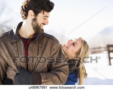 Young woman embracing man in winter View Large Photo Image Stock Image - Young woman embracing man in winter. Fotosearch