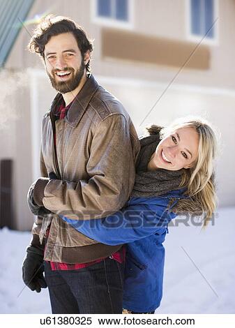 Stock Photography - Young woman embracing man in winter. Fotosearch