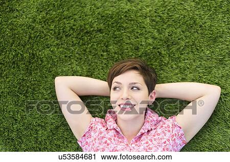 Stock Image - Young woman lying on grass. Fotosearch