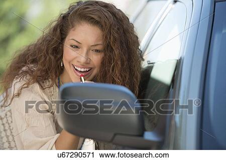 Young woman putting lipstick looking at rear mirror View Large Photo Image Stock Image - Young woman putting lipstick looking at rear mirror. Fotosearch