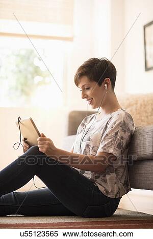Stock Photography - Young woman sitting on floor and using tablet pc. Fotosearch