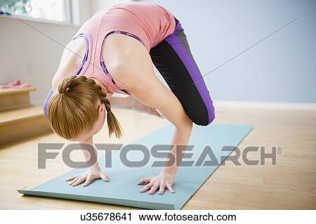 Stock Image - Young woman standing on hands. Fotosearch