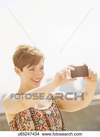 Young woman taking selfie with mobile phone View Large Photo Image Picture - Young woman taking selfie with mobile phone. Fotosearch