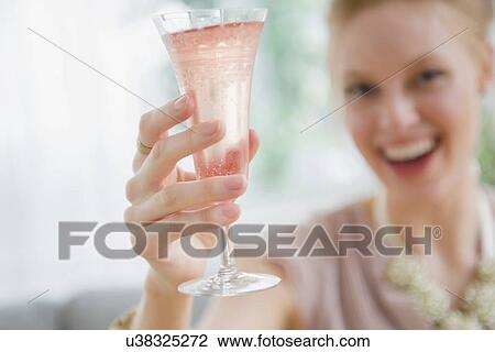 Stock Image - Young woman toasting with champagne. Fotosearch