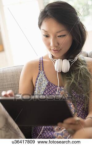 Stock Photo - Young woman using digital tablet at home. Fotosearch