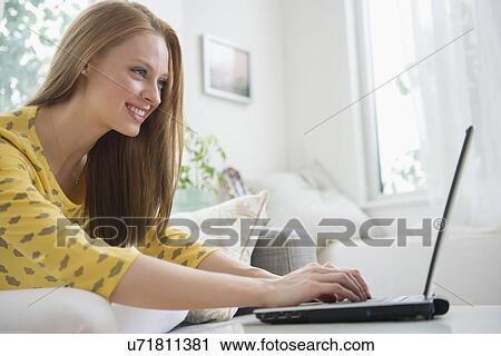 Young woman using laptop in living room View Large Photo Image Stock Image - Young woman using laptop in living room. Fotosearch