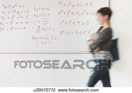 Stock Image - Young woman walking in front of whiteboard. Fotosearch