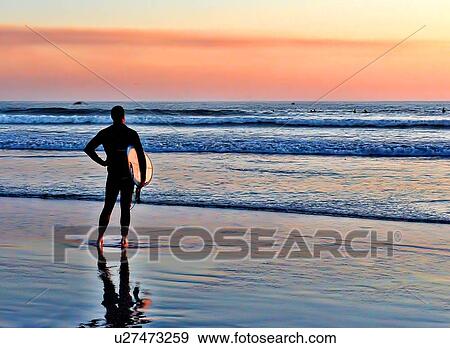 Man holding surfboard looking out at the ocean View Large Photo Image Stock Photo - Man holding surfboard looking out at the ocean. Fotosearch