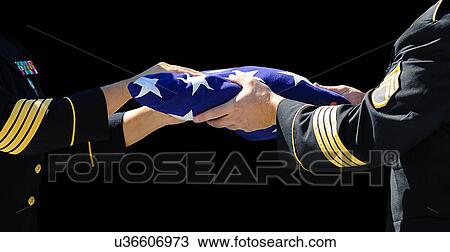 Stock Image - Soldiers handing a folded American flag. Fotosearch