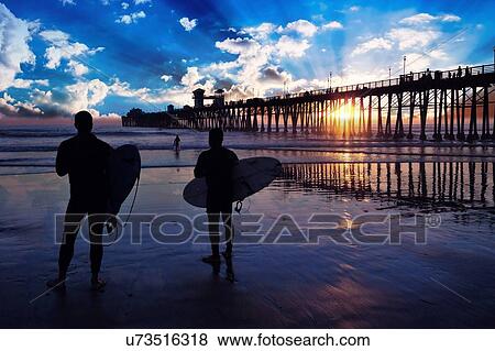 Surfers at sunset View Large Photo Image Stock Photo - Surfers at sunset. Fotosearch