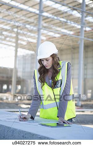 Stock Photography - Architect adjusting blueprint on construction site. Fotosearch
