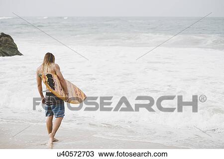 Stock Image - Australian surfer with surfboard, Bacocho, Puerto Escondido, Mexico. Fotosearch