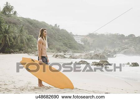 Stock Image - Australian surfer with surfboard, Bacocho, Puerto Escondido, Mexico. Fotosearch