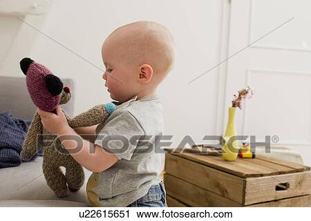 Baby girl pointing playing with teddy bear in sitting room View Large Photo Image Stock Image - Baby girl pointing playing with teddy bear in sitting room. Fotosearch