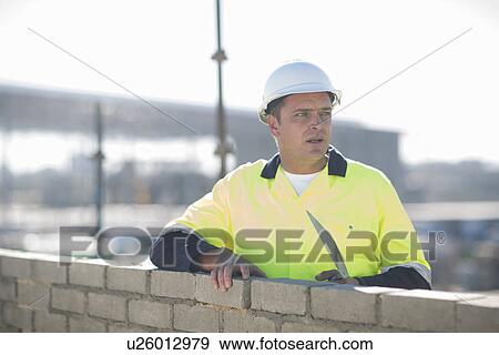 Brick layer using trowel on construction site wall View Large Photo Image Stock Photo - Brick layer using trowel on construction site wall. Fotosearch