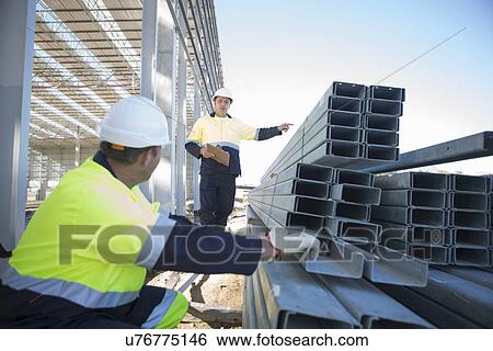Builder and site manager checking girders on construction site View Large Photo Image Stock Photograph - Builder and site manager checking girders on construction site. Fotosearch