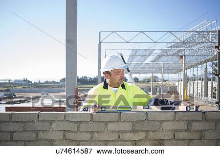 Stock Photo - Builder using spirit level on construction site wall. Fotosearch