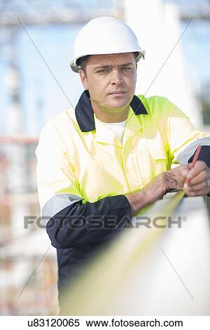 Builder using tape measure on construction site wall View Large Photo Image Stock Photography - Builder using tape measure on construction site wall. Fotosearch