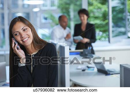 Businesswoman chatting on smartphone in office View Large Photo Image Stock Image - Businesswoman chatting on smartphone in office. Fotosearch