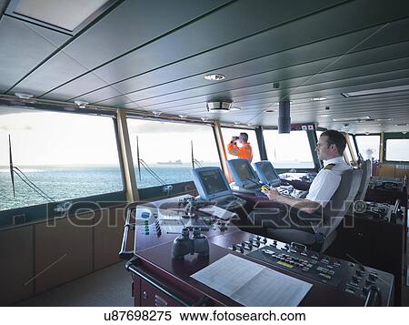 Captain and worker on bridge steering ship at sea View Large Photo Image Stock Photography - Captain and worker on bridge steering ship at sea. Fotosearch