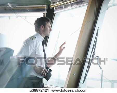 Captain looking out of window on ship's bridge View Large Photo Image Stock Image - Captain looking out of window on ship's bridge. Fotosearch