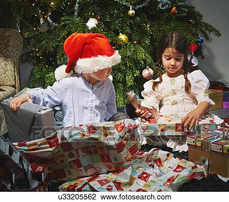 Stock Image - Children opening christmas gifts. Fotosearch