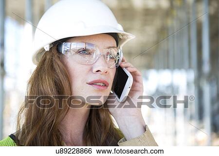 Stock Photograph - Close up of architect chatting on smartphone on construction site. Fotosearch