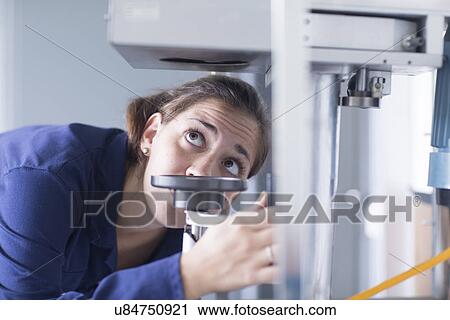 Stock Image - Close up of female engineer examining machine valve in factory. Fotosearch