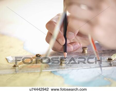 Stock Image - Close up of navigator checking charts on ship's bridge. Fotosearch