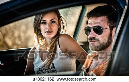 Stock Image - Close up of young couple through car window. Fotosearch