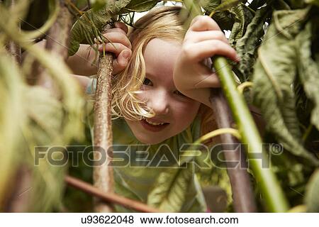 Stock Photo - Close up portrait of girl hiding in bushes. Fotosearch
