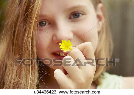 Stock Image - Close up portrait of girl holding dandelion flower. Fotosearch