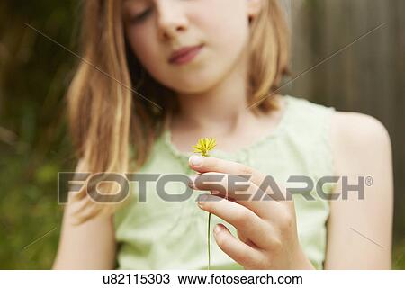 Stock Image - Cropped shot of girl with holding dandelion flower. Fotosearch