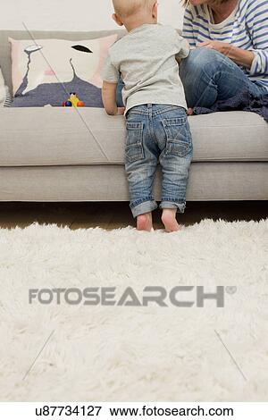 Stock Photo - Cropped shot of mature mother and baby daughter in sitting room. Fotosearch