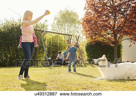 Stock Photo - Family in garden training dog. Fotosearch