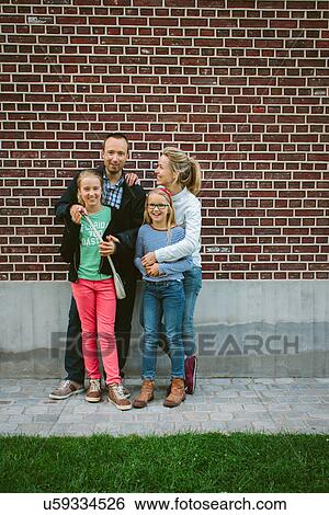 Stock Photograph - Family standing by brick wall. Fotosearch